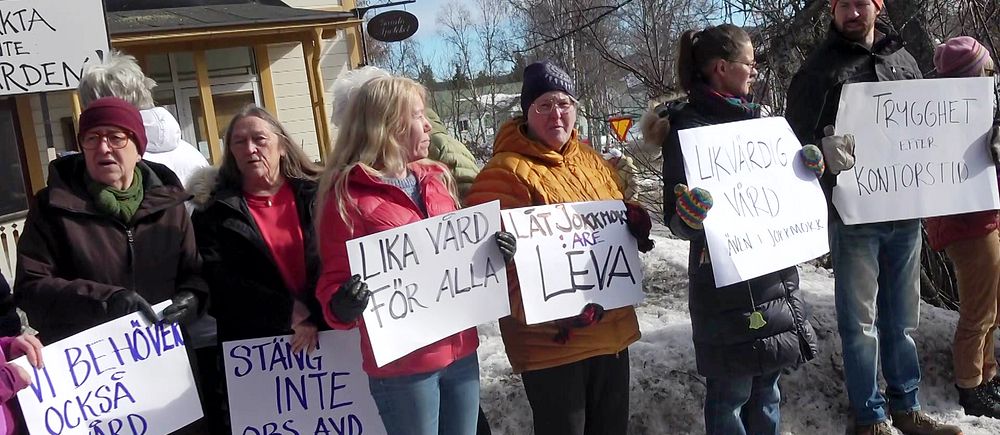 Flera Jokkmokksbor håller upp plakat under demonstrationen vid kommunhuset.