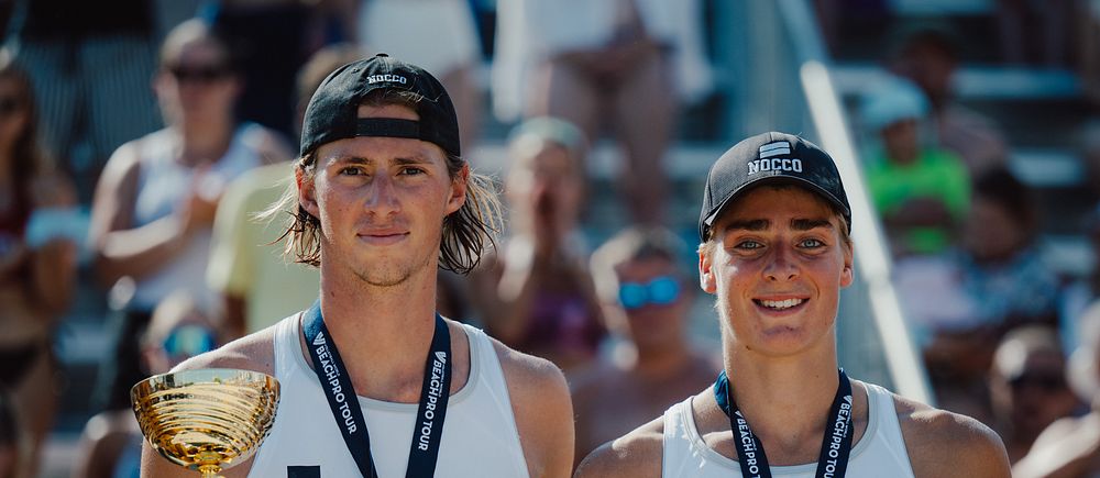 Jacob Hölting Nilsson och Elmer Andersson poserar med pokaler efter beachvolleybollseger.