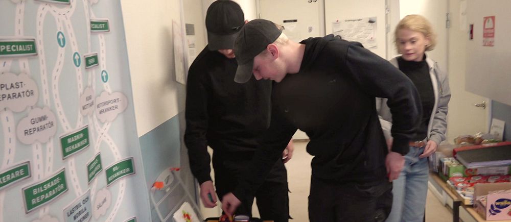 två tonårskillar plockar kondomer från en låda i en korridor