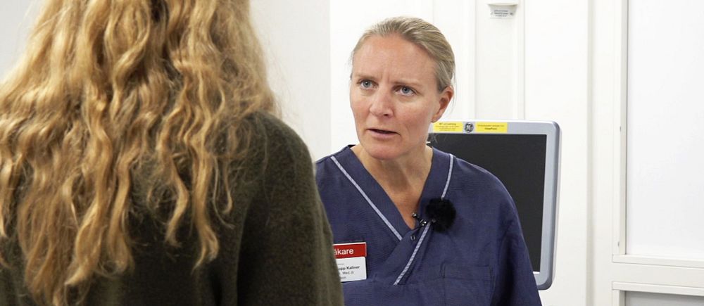 Sjuksköterska samtalar med person i vårdmiljö och håller läkemedelsförpackningar i handen.