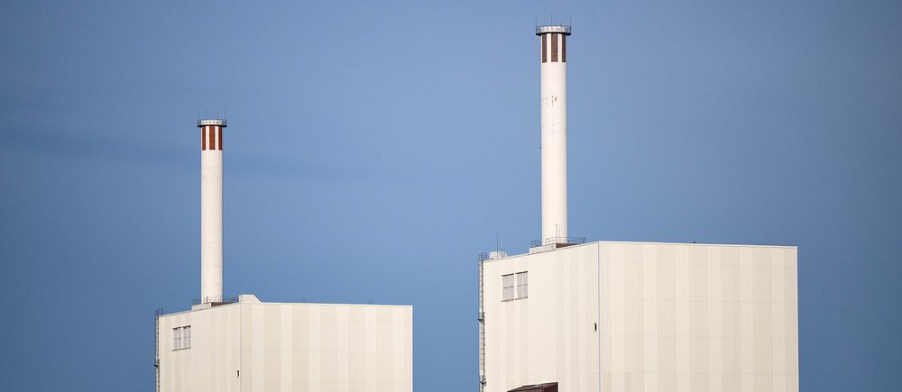 Kärnkraftverk med två vita reaktortorn mot klarblå himmel.