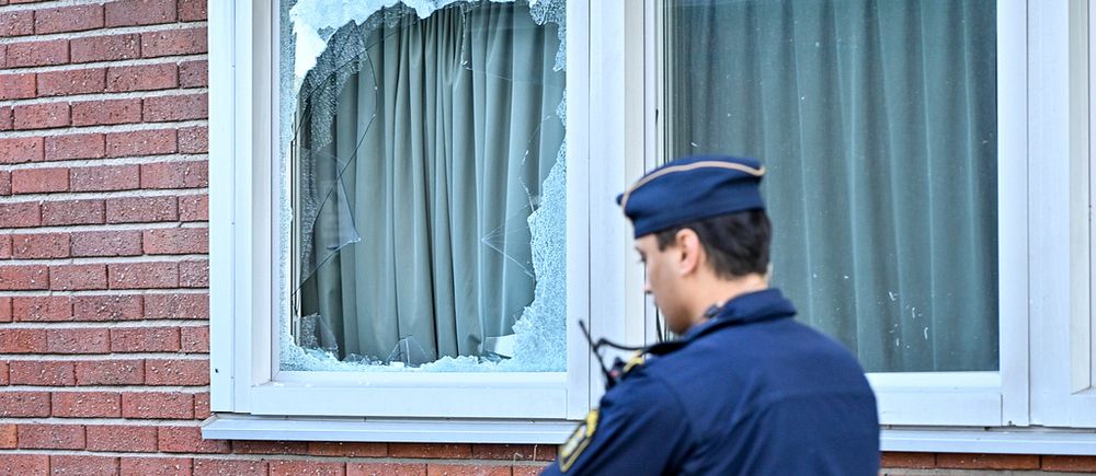 Polis och en fasad med krossat fönster