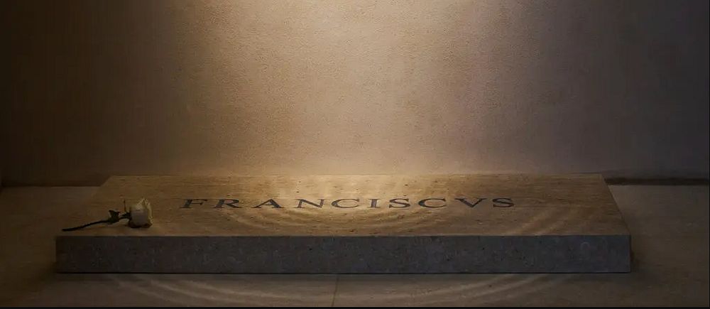 Enkel bild. En belyst gravsten med texten ”Franciscus” mot en enkel, ljus bakgrund.