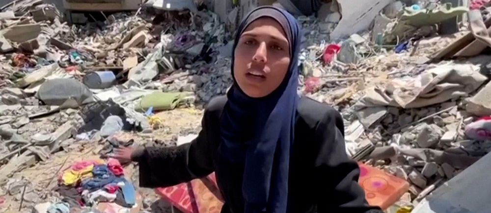 En palestinsk kvinna som står mitt i rasmassor av hus.
