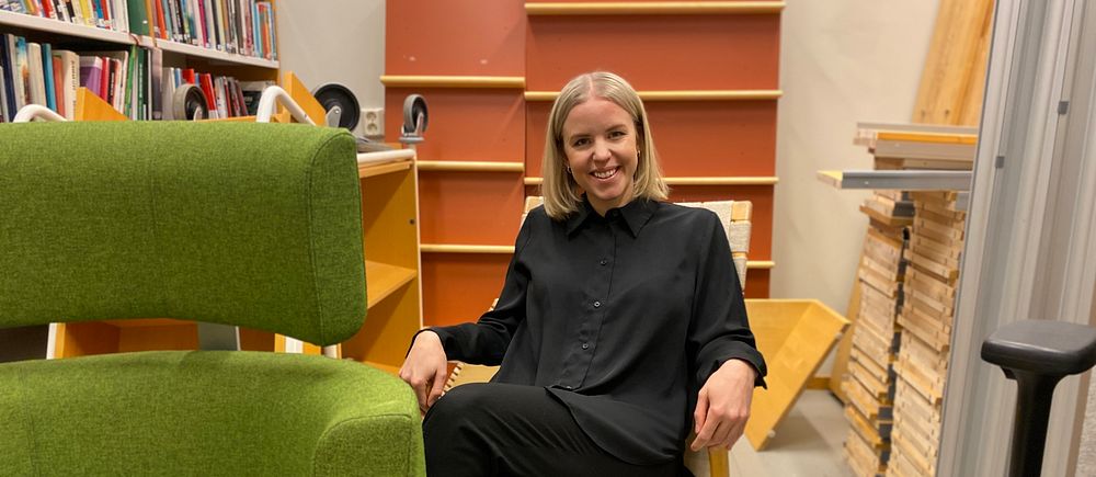 Person sitter i stol omgiven av bokhyllor och möbler i ett bibliotek eller bokhandel.