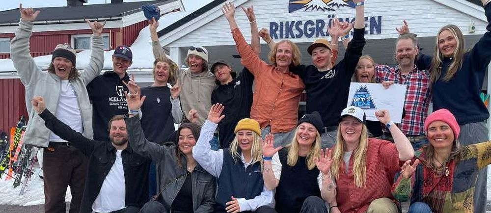 Glada personer poserar med diplom framför entrén till Riksgränsen på vintersäsong.
