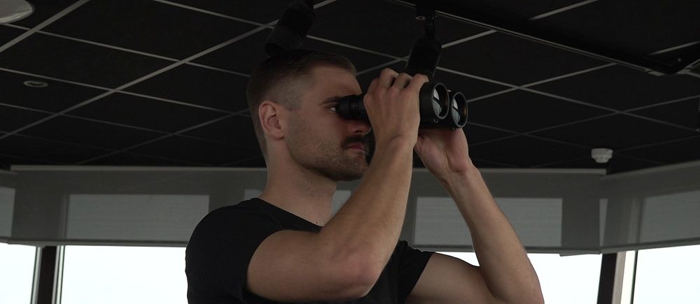 Flygledaren Viktor Ekberg tittar ut från flygledartornet med en kikare