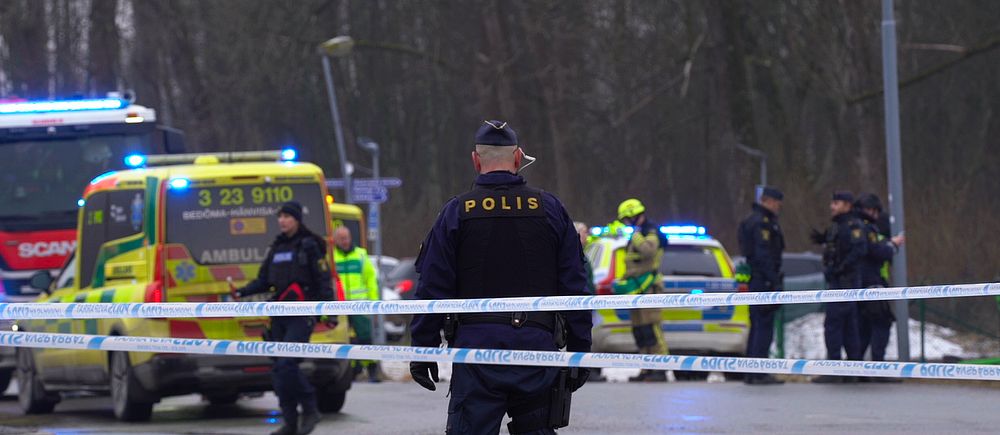 Polisavspärrning vid en väg med ambulanser och polisnärvaro i bakgrunden.
