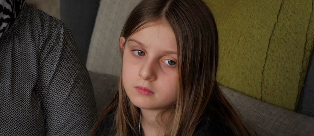 Nioåriga flickan Lisa med långt brunt hår sitter i soffa, berättar om känslorna kring  att utvisas till Albanien trots att hon är född i Sverige