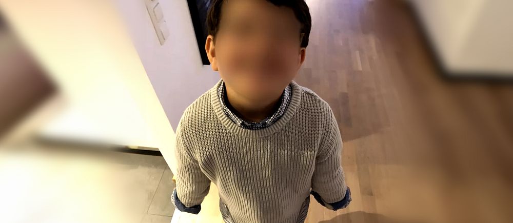 Barn i vit tröja fotograferad från ovan i ett rum med trägolv.