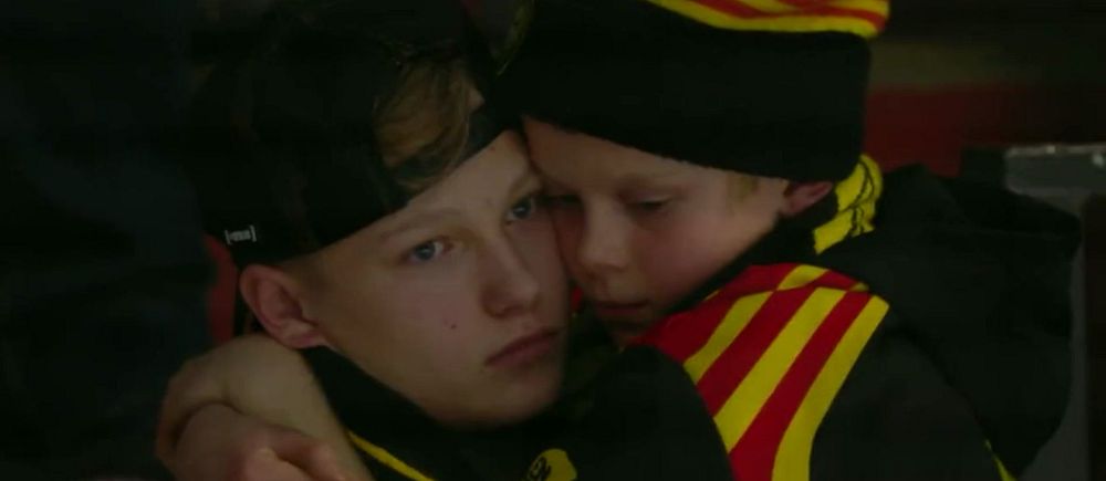 Person i publiken i randig mössa kramar om någon i liknande färger.
