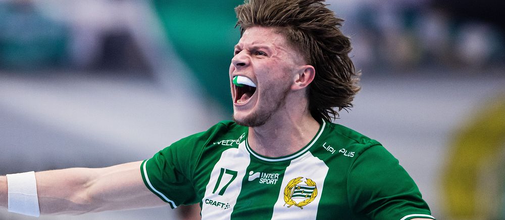 Fotbollsspelare i grönvitrandig tröja firar med utsträckta armar på planen.
