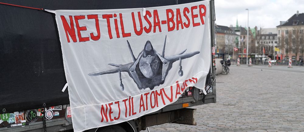 Banderoll med texten ”Nej til USA-baser, nej til atomvåben” och bild på ett militärflygplan.