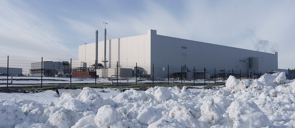 Stor fabrik i vinterlandskap med snö framför byggnaden.