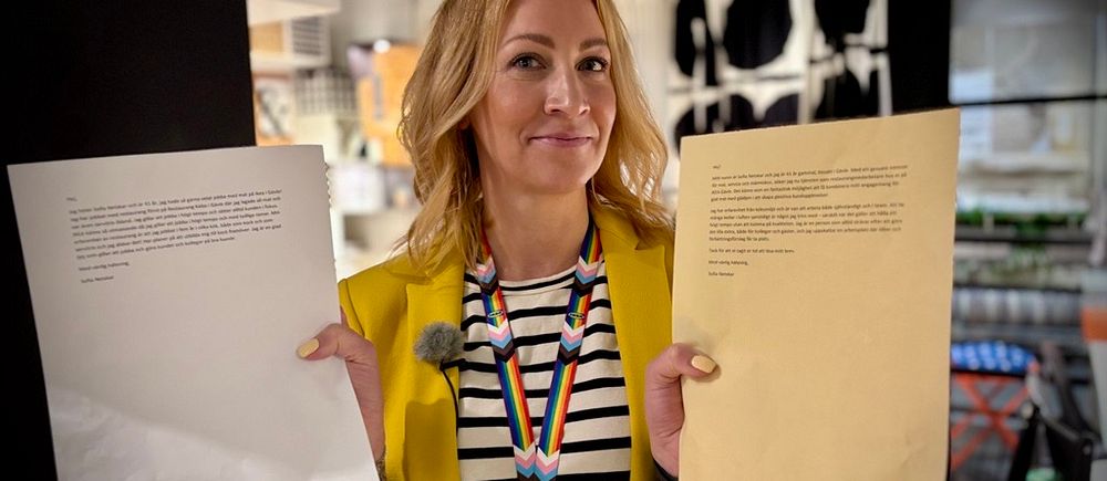 Person i gul kavaj håller upp två papper inne i en möbelaffär.