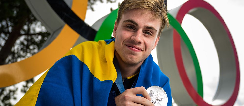 Bordtennisstjärnan Truls Möregårdh med sin olympiska silvermedalj om halsen och svenska flaggan om ryggen.