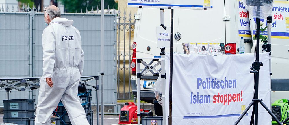Polis går förbi affisch vid scen med orden ”Politischen Islam stoppen!”