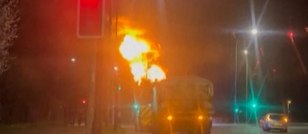Brand bakom lastbil vid ett trafikljus. Röd ljussignal lyser, andra fordon passerar.