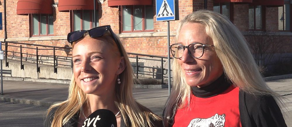 Två kvinnor intervjuas av SVT framför en tegelbyggnad med röda markiser.
