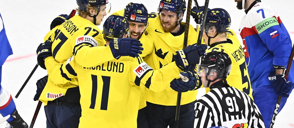 Svenska ishockeyspelare i gula tröjor firar mål mot ett lag i blå och röd utrustning.