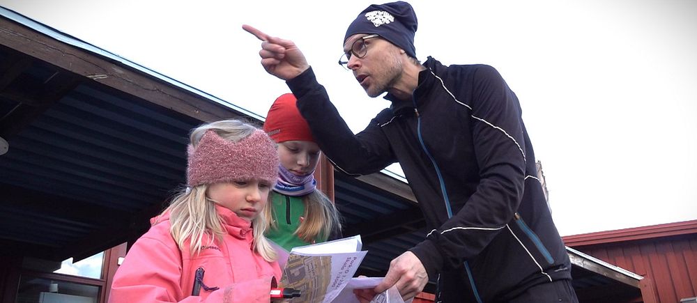 En pappa beskriver för sina döttrar hur man ska läsa kartorna inför starten på parkorienteringen.