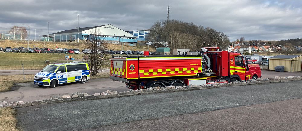 Polisbil och brandbil står parkerade vid en vägkant framför en idrottsanläggning i Partille.