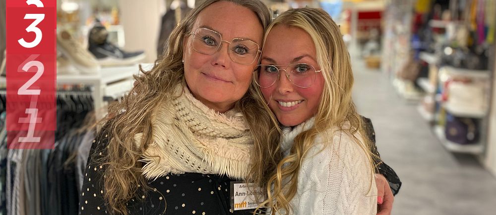 Två personer omfamnade i en butik med kläder i bakgrunden.