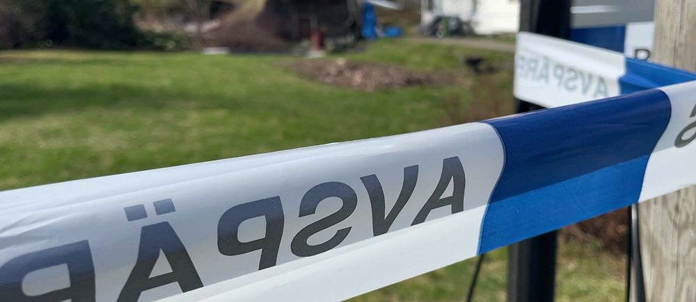 Polisens avspärrningsband runt villatomt i bostadsområde.