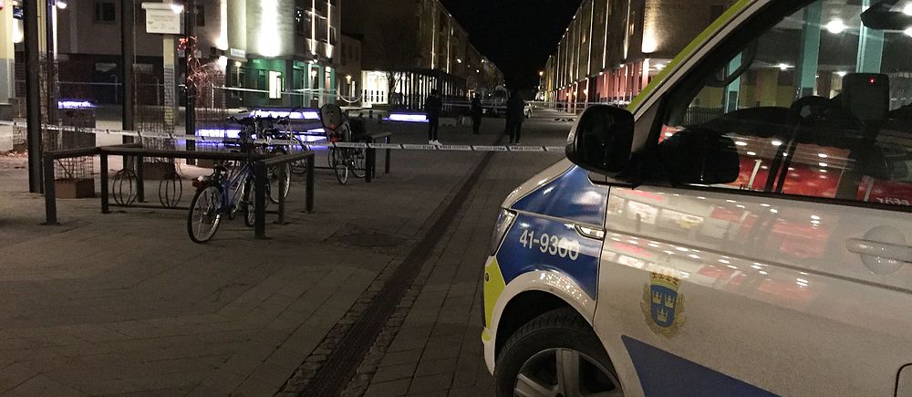 Polisbil och avspärrningsband på nattlig gata.