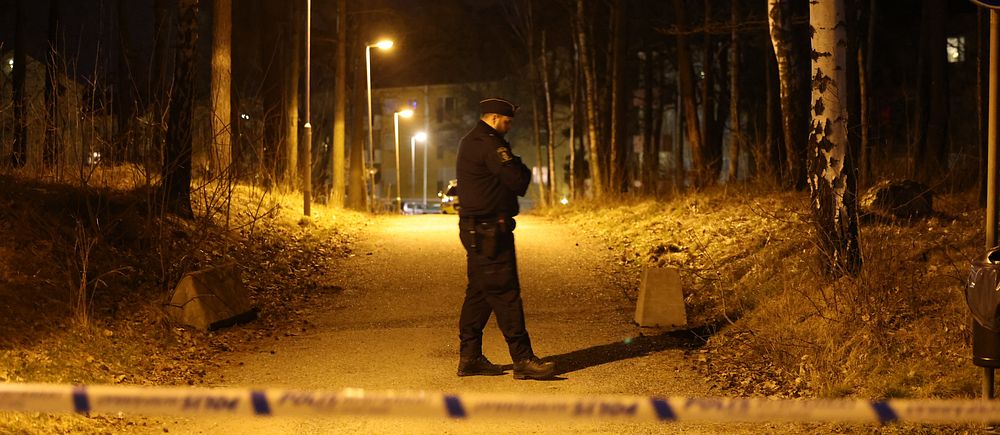 En polis står bakom avspärrningar i ett skogsparti.
