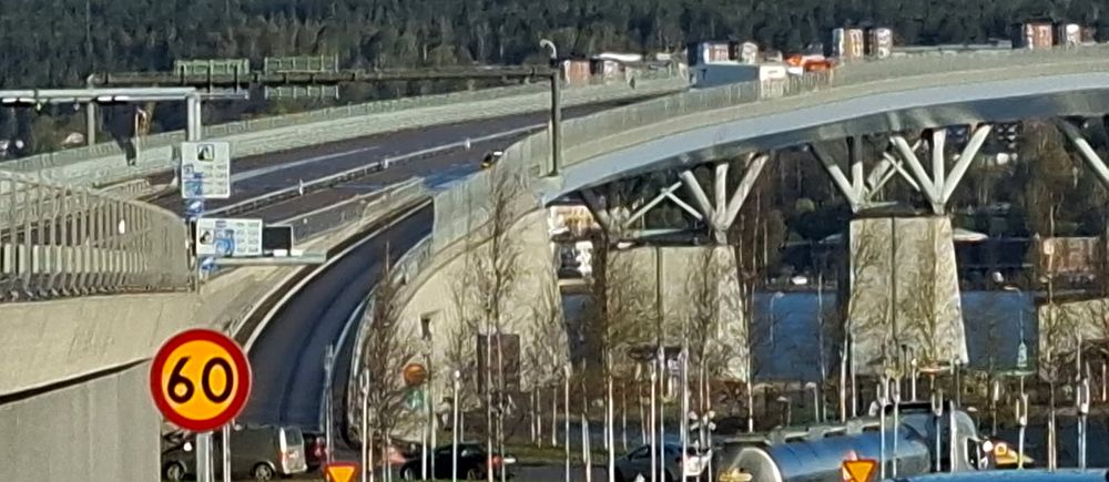 Motorvägsbro med 60-skylt, bilar i förgrunden och skog i bakgrunden.