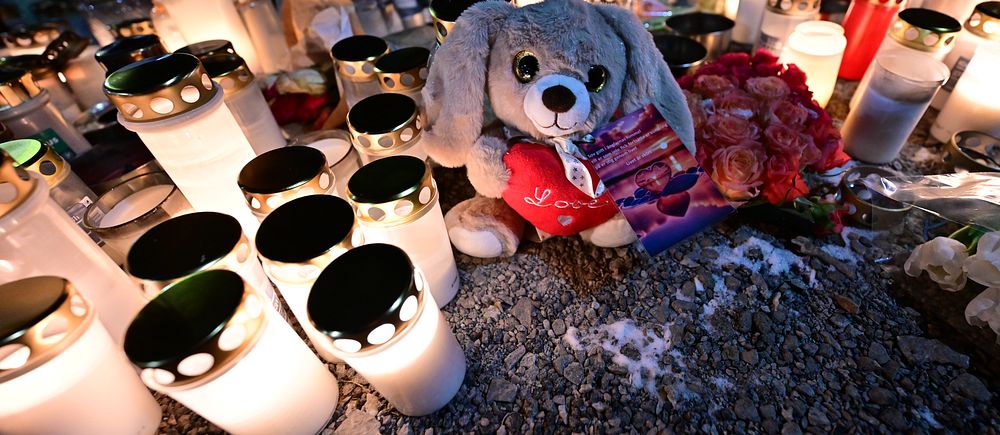 Ljusstakar och gosedjur placerade på marken i en minnesgärning.