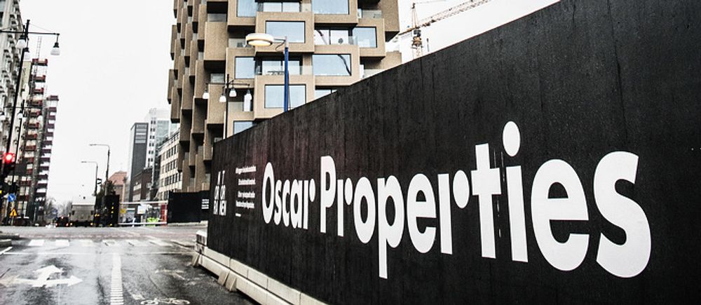 En bild på en vägg längs en väg där det står Oscar Properties med stora bokstäver.