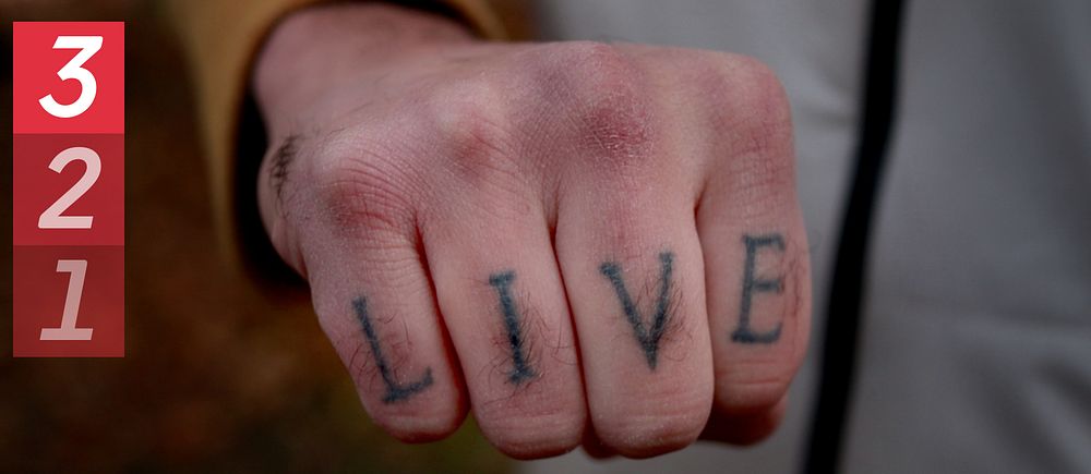Hand med tatuering där det står ”live”