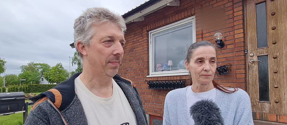 Två personer intervjuas med mikrofon utanför ett rött tegelhus i Klippan efter det misstänkta dubbelmordet.