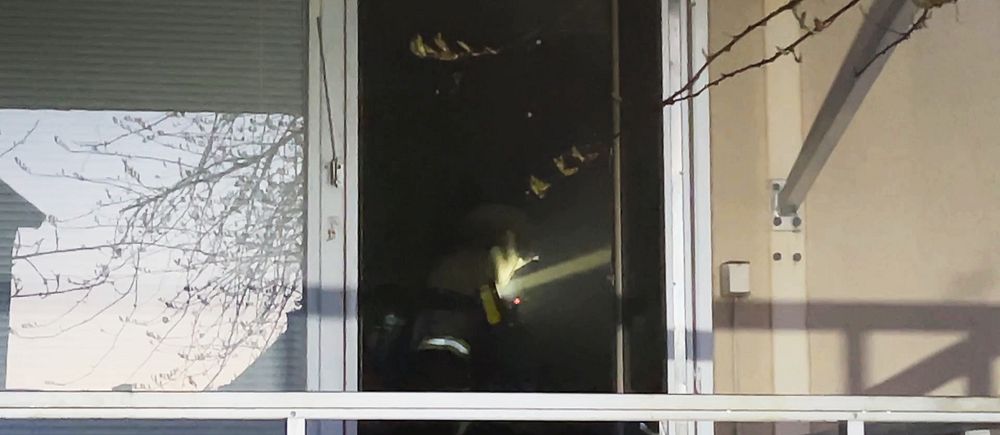 En rökdykare i ett rökfyllt rum syns genom en balkongdörr