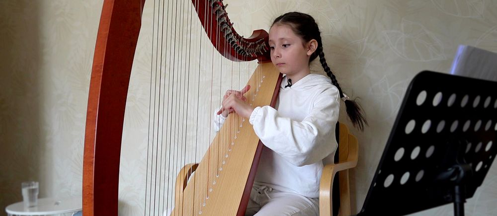 Diana Pyliavska, 9 år, sitter vid sin harpa i bostaden i Luleå.