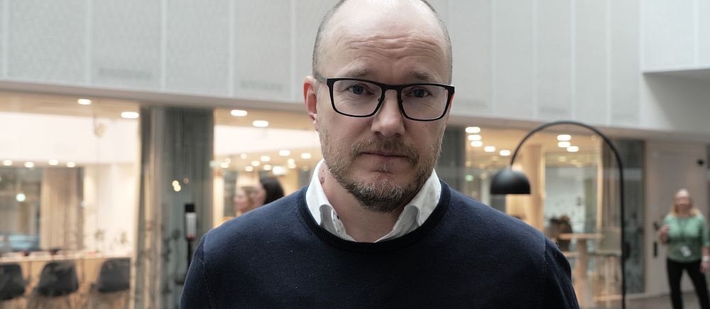 Person i kontorsmiljö med glasväggar och modern inredning.