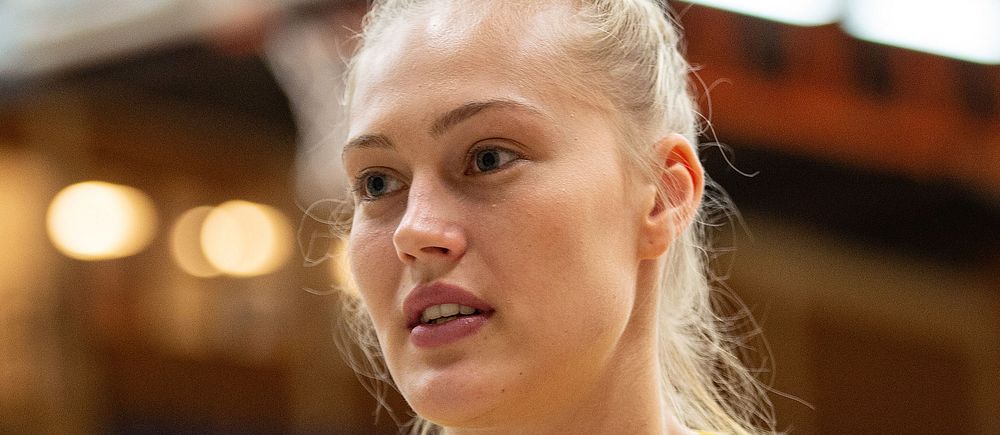 Svensk basketspelare i gul matchtröja på inomhusarena.