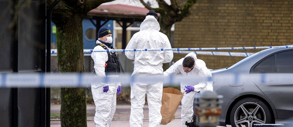 Kriminaltekniker undersöker område vid polisavspärrning bredvid en bil på gata.