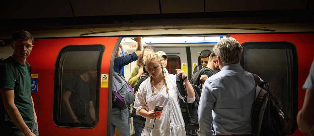 Folk kliver av och på ett tunnelbanetåg vid en hållplats.