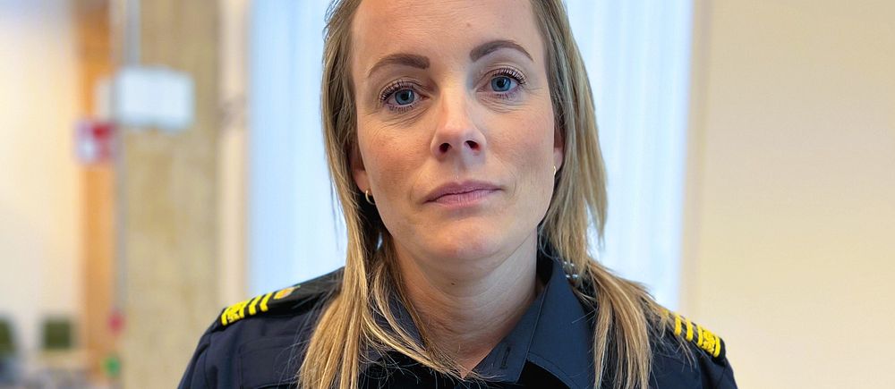 Svensk polis i uniform står inomhus med suddig bakgrund.