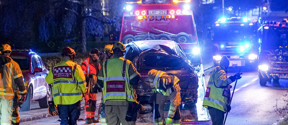 Räddningspersonal i varselklädsel på gata genom Brösarp i Tomelilla kommun, där en förstörd bil bärgas efter en allvarlig trafikolycka