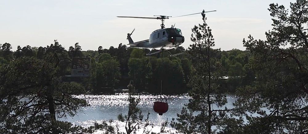 Helikopter hämtar vatten för att bekämpa skogsbrand i Sollentuna.