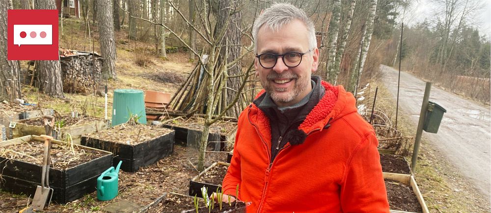 Johannes Wätterbäck, också känd som Farbror Grön, står vid sina odlingar iklädd orange fleecetröja. I händerna har han plasttråg med olika sådder. Han ser glad ut.