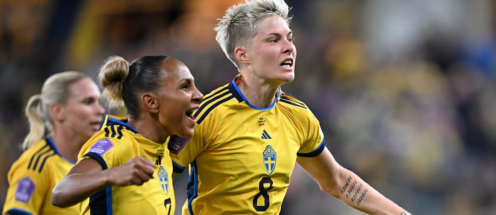 Svenska fotbollsspelare firar mål på planen. Spelare i gul tröja med nummer 8, Lina Hurtig, i fokus.