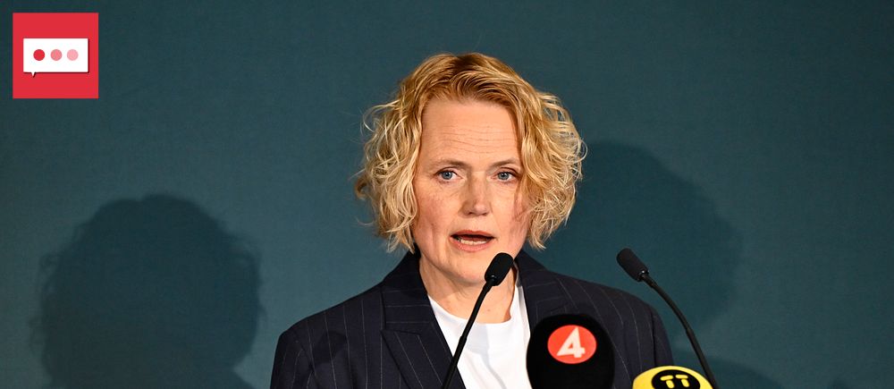 Person vid talarstol med mikrofoner och tv-mikrofoner från TV4 och SVT framför sig.