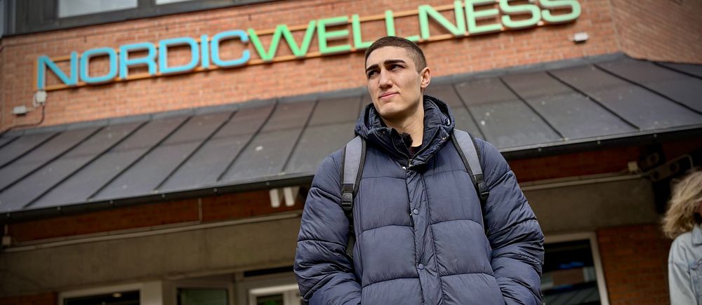En kille med dunjacka står utanför gymmet i Angered