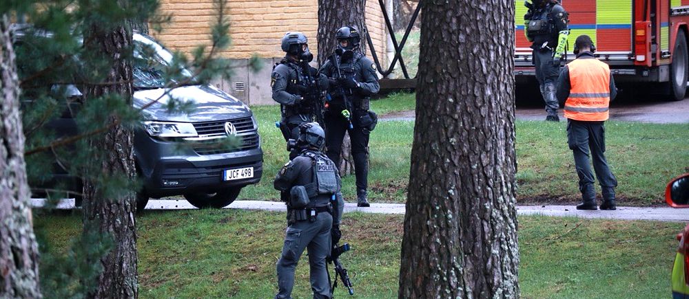 Tungt beväpnade poliser smyger mellan träd under övning
