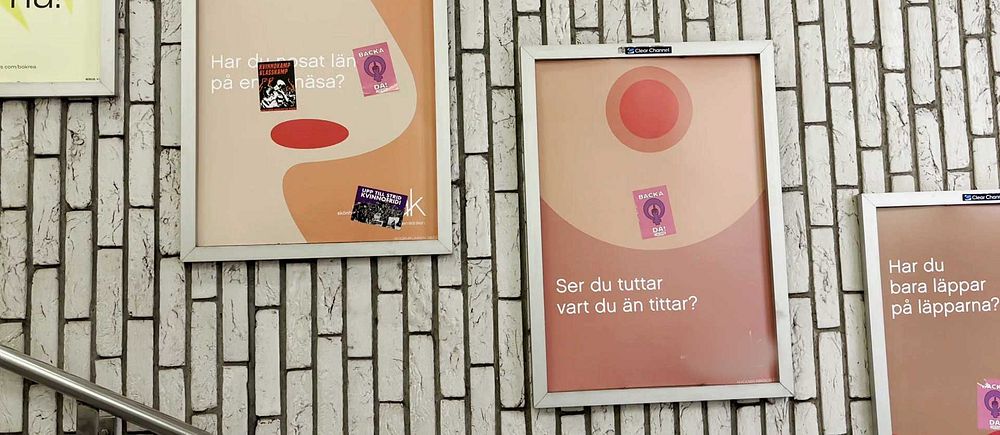 Två reklamaffischer med abstrakt design och klistermärken på tegelvägg inomhus.